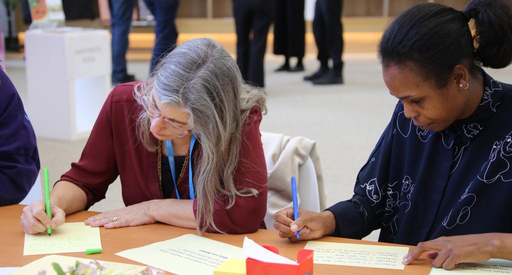 Picture of two ladies writing on paper.