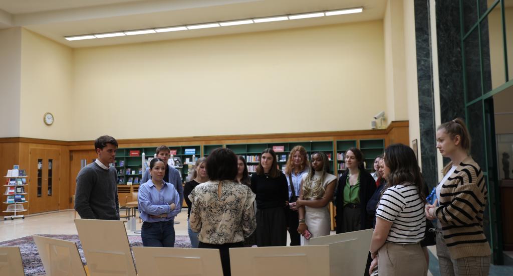 This photo shows the students on a Library tour, as they listen to a Librarian explain the history of the UN Library & Archives Geneva.