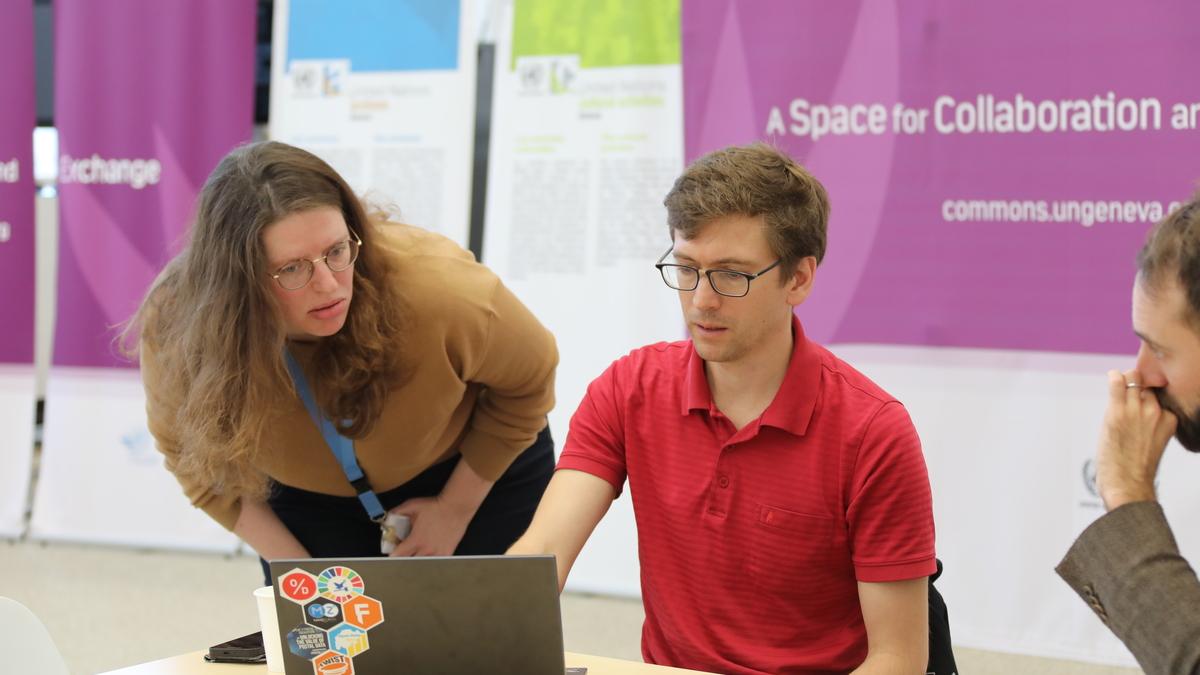 This is a photo from the day of the hackathon. A librarian assists one of the participants with a question as they look at resources on a laptop.