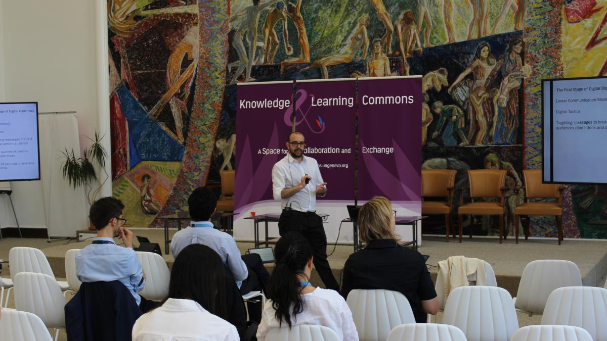 Picture of a man speaking in front a room 