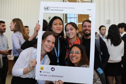 This is a photo from the event. It shows four young women who attended the event, posing with the Commons Instagram frame. Other guests are featured in the background. 