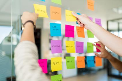 Business people arranging various adhesive notes with text glass office