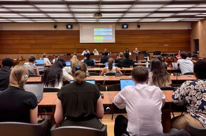 This photo shows an audience in a conference room at UN Geneva, listening to young graduate students present on the occasion of the UN's 80th anniversary.